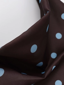 Macro view of brown fabric with blue polka dots showing satin texture and smooth drape