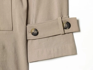 Detail of khaki trench coat cuff with adjustable strap and dark marble buttons
