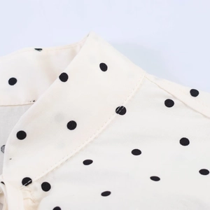 Detailed close-up of the collar stitching and black polka dot pattern on poplin fabric