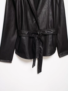 Detail of black leather coat featuring premium lychee texture and belted waist design