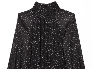 Detailed close-up of a high-neck pleated collar on a black and white polka dot chiffon dress