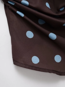 Close-up of brown polka dot fabric with blue dots and smooth silky texture finish