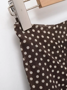 Detailed close-up of brown polka dot skirt fabric with lightweight vertical texture