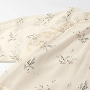 Dettaglio della camicetta in chiffon con stampa fogliame grigio e bordi a balze
