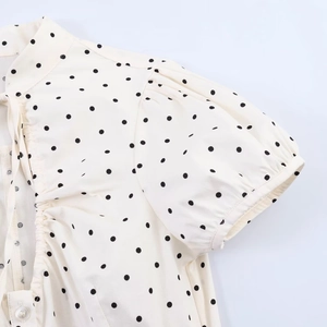 Detail of puff short sleeves and black polka dots on cream women poplin top