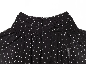 Close-up of pleated chiffon waist detail and invisible zipper on black polka dot dress
