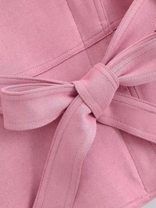 Détails de la veste en daim rose montrant la ceinture nouée et les finitions de couture