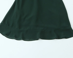 Détail de l'ourlet à volants sur une robe cintrée en mousseline vert foncé pour femme