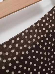 Detail of dark brown polka dot fabric with light texture on a wooden hanger