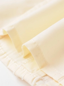 Détail d'une chemise en popeline crème montrant la texture du coton et les coutures