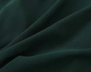 Vue macro du tissu mousseline vert foncé montrant une texture fine et des drapés