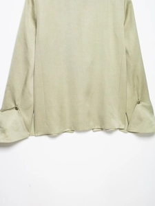 Detail of sage green blazer sleeve with tiered cuff and vintage metal button closure