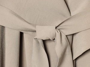 Close-up of knotted waist belt on khaki French style short trench coat for women