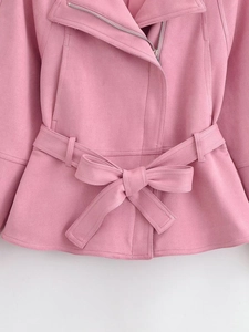Détail de veste en daim rose avec fermeture éclair diagonale et ceinture à nouer