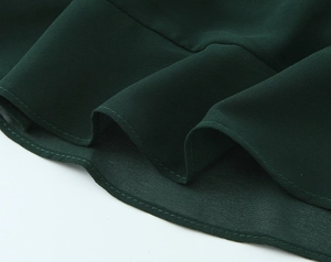 Détail de l'ourlet à volants vert foncé avec une finition de bord ondulé à double couture