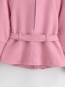 Gros plan sur la veste en daim rose montrant la ceinture et l'ourlet volanté