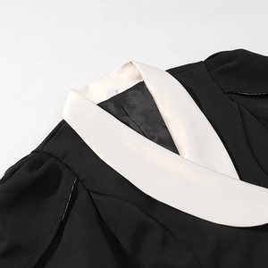 Détail rapproché du col châle contrasté en V sur cet ensemble ajusté noir et blanc