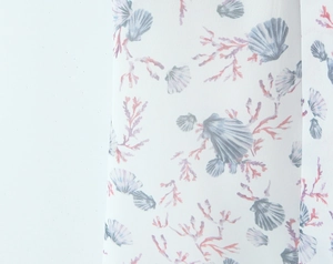 Close-up detail of soft watercolor fabric featuring sea shells and coral patterns