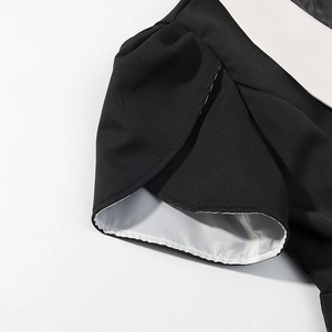 Gros plan du revers de manche en forme de pétale avec couture contrastée noir et blanc