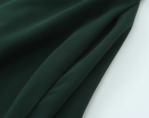 Vue détaillée de la texture du tissu mousseline vert foncé avec volants et drapé