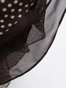 Detail of sheer chiffon fabric with classic white polka dots and delicate rolled hem
