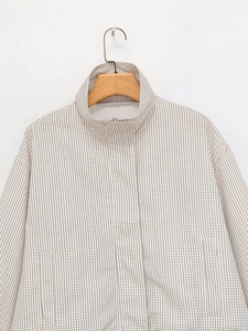 Détail de la veste à carreaux avec col montant, zip caché et emmanchures tombantes