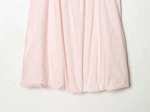 Close-up of light pink bubble hem dress featuring pleated balloon-style design and soft texture