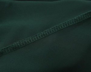 Détail du bord d'une robe en mousseline vert foncé avec couture surjetée soignée