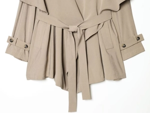 Detail of khaki trench coat featuring drawstring waist and sleeve cuffs with dark buttons