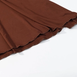 Detail of dark brown knit dress featuring a delicate lettuce edge hemline finish