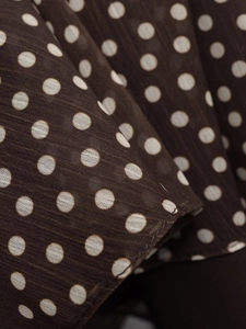Detail of dark brown polka dot chiffon fabric with fine pleated texture and grid weave