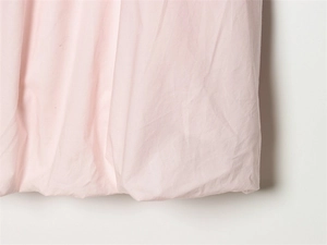 Detailed macro view of light pink fabric texture with natural pleated folds on a dress