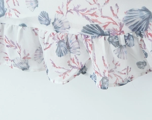 Detail of ruffled chiffon hem with blue scallop and pink coral prints on summer dress