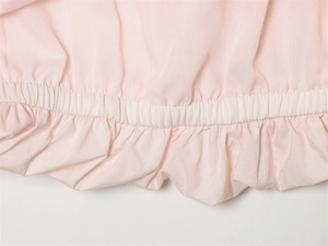 Detail of light pink dress featuring elastic ruched waist and soft cotton fabric texture