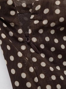 Macro view of a seamless invisible zipper on a brown polka dot patterned fabric