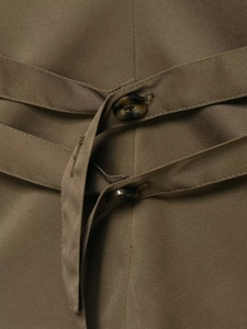 Detail of olive green waistcoat featuring cross-strap design and marble pattern buttons