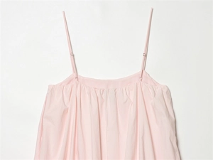 Detail of adjustable spaghetti straps and ruffled neckline on pale pink dress