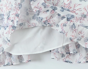 Detail of floral chiffon dress with ocean coral prints and delicate ruffled hemline