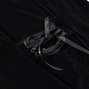Detailed view of black velvet top featuring lace-up design with satin ribbons and metal eyelets