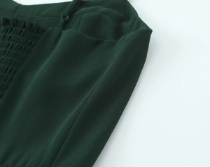 Détail de la robe vert foncé montrant la texture froncée et la fine bandoulière
