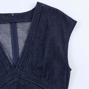 Détail d'une robe en jean bleu foncé avec col en V ajouré et fermeture éclair invisible