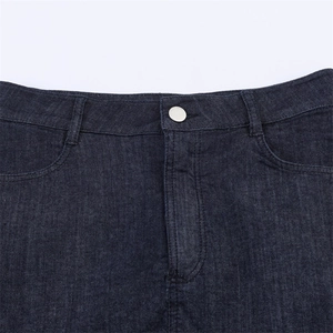 Dettaglio della vita su gonna in denim blu scuro con bottone in metallo argentato e passanti