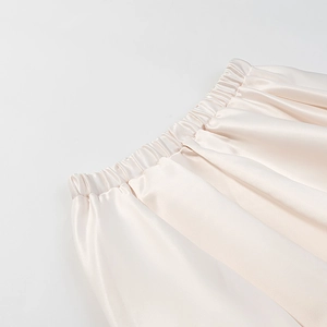 Détail de la taille élastique sur jupe en satin crème soyeux avec plis verticaux