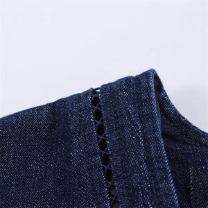 Détail de robe en denim bleu foncé avec broderie en dentelle et coutures à double aiguille