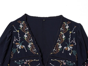 Close-up of deep V-neck blouse with colorful floral embroidery and size XS label detail