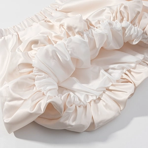 Détail de la texture satinée ivoire avec bordure plissée élastique et éclat de soie doux