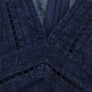 Détail de robe en jean bleu foncé avec broderie ajourée et fermeture éclair sur col en V