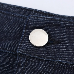 Dettaglio vita in denim scuro con bottone in metallo argento lucido e cuciture rinforzate