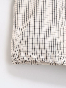 Gros plan sur la texture du tissu à carreaux et les coutures de cet ensemble en nylon