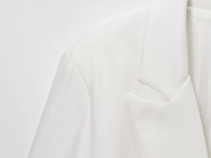 Macro detail of white blazer showing notched lapel and fine twill linen blend fabric texture